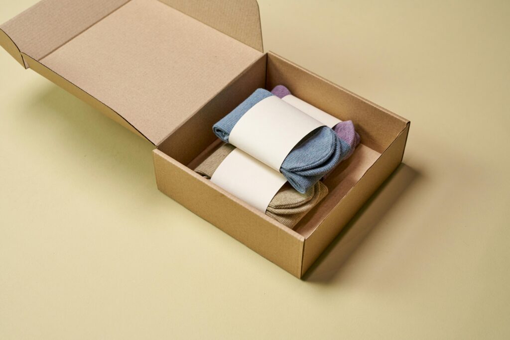 pexels-photo-9594145-9594145 Multicolored socks neatly arranged inside open cardboard packaging on a neutral background.